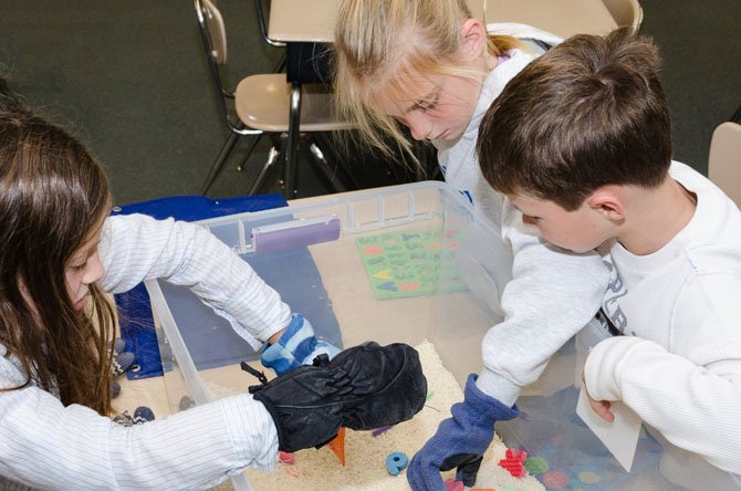Students from Wayside Elementary School in Potomac wear mittens while trying to pick up small objects in a container. The activity, which is part of the school’s Special Needs Awareness Week, is designed to simulate sensory deprivation.

