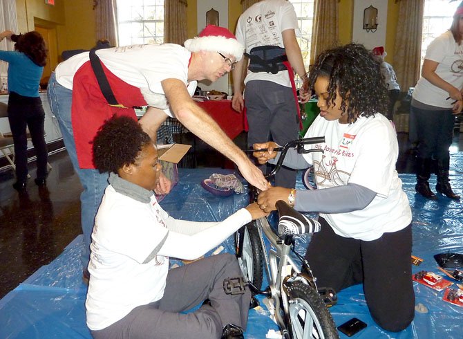 Wheel Nuts Bike Shop owner Ron Taylor, standing, helps volunteers Chariolett Johnson and Linda Powell assemble a bike during the Alexandria Cares Bows, Baskets and Bikes event.