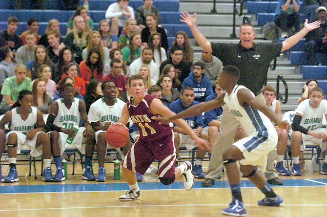 Oakton guard Thomas Tribble drives against South Lakes guard Brandon Kamga in front of South Lakes Head Coach Andrew Duggan and the Seahawks’ bench on Nov. 29.