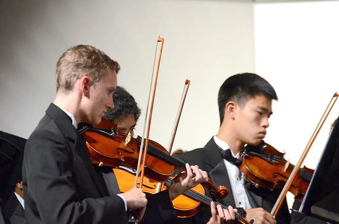 Langley High School Orchestra violinists, from left: Tim Kostelancik, Kurt Tran (hidden), Quan Pham. 