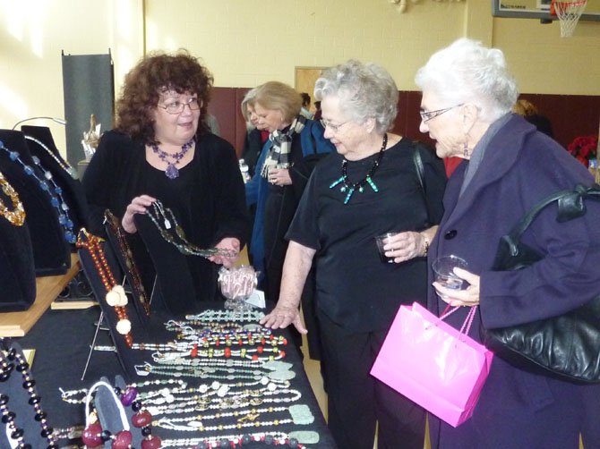 Artisan Cathy Harl, left, showcases her latest works to shoppers Patricia Harl and Pat Libhart at last year’s Holiday Market to benefit the city’s women’s programs.
