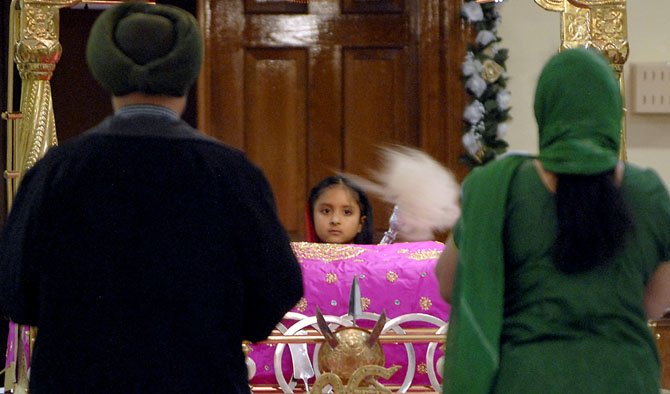 A child and her parents during prayer services at the Sikh Foundation of Virginia in Fairfax Station on Thursday, Nov. 14. The Dias where Guru Granth Sahib (the Holy Book) is adorned is called Darbar Sahib (Holy Court).