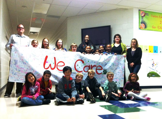 From left—OES Librarian Kevin Hjelm, PTA president Alysia Dempsey, and PTA volunteers Tammy DiBlasi and Mary Pat Julian help students hold up the 10-foot “We Care” banner displayed during the school’s Book Fair last week.