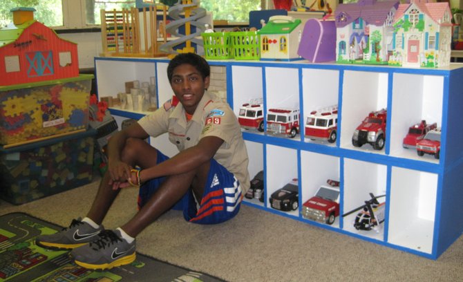 Suddy Sriram of Troop 869 sits in front of the shelves, which he built as part of his Eagle Scout Project in the summer of 2012.
