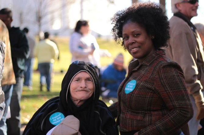 An individual with a disability and his caregiver wearing ‘I Support The New Virginia Way’ stickers at the Martin Luther King Day Rally in Richmond.