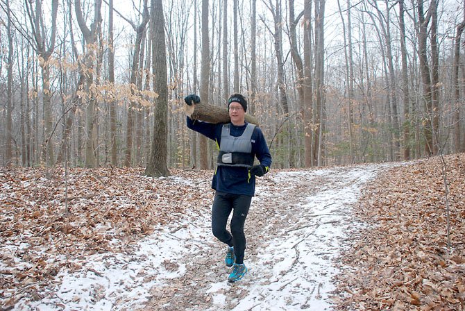 Burke resident Lance Sanson trains for the Spartan Death Race by jogging on Fountainhead Regional Park with a log over his shoulder.