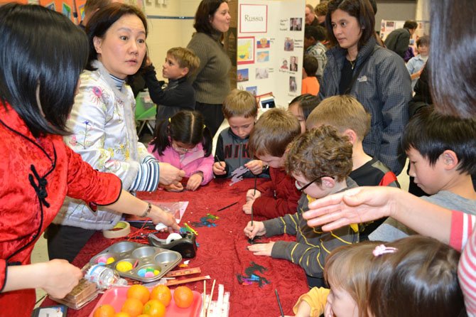 Chesterbrook Chinese teachers Peggy Leung and Beesha Hung show students how to make Chinese New Year ornaments.