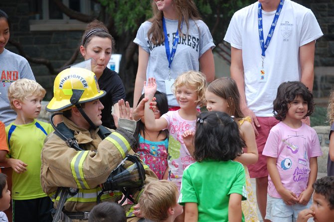 Student attending the Norwood School summer camp in Bethesda, Md., spend time with a firefighter.
