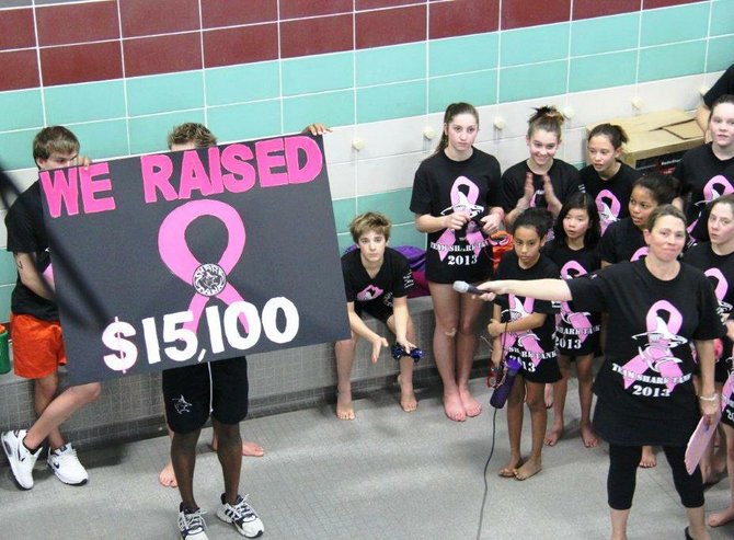 Shark Tank swimmers gather around coach Patty Friedman, co-founder of the team, as she announces the fundraising total for the Sunday, March 3, marathon to raise funds and awareness for breast cancer.