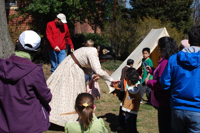 Kecia Wolf, a Fairfax resident and school social worker in Prince William County, demonstrates her period-correct “pecking hen” toys with a couple of young historians. Wolf volunteers with the 17th Virginia Infantry Fairfax Rifles and appeared as Joshua Gunnell’s civilian wife, who is credited with distracting Confederate soldiers during the raid while her husband fled under the family house.