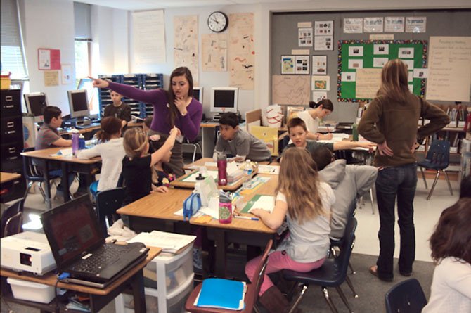 Senior Aleena Gharib talks to a student who has questions about one of the lessons while students file into the classroom after a short break.