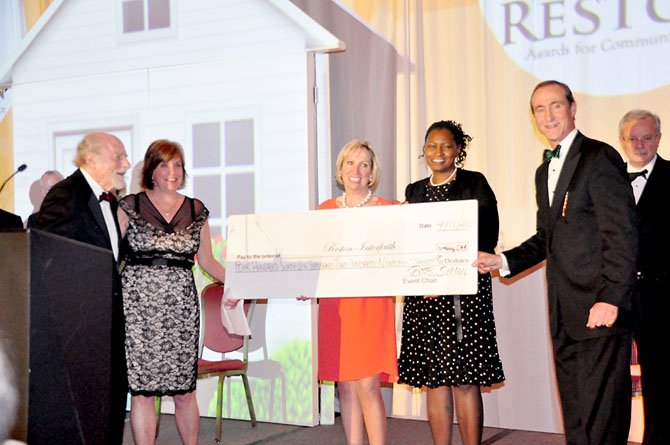 From left, Reston founder Robert Simon, Reston Interfaith CEO Kerrie Wilson, Jane Raymond, chair-elect of the Greater Reston Chamber of Commerce, Angela Harpalani, chair of Reston Interfaith, and Mark Ingrao, president of the Greater Reston Chamber of Commerce present a check for $466,293, the money raised for Reston Interfaith at the 22nd annual Best of Reston awards. 