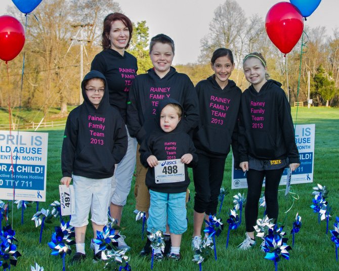 SafeSpot founding board member and mom Bridget Rainey and members of The Rainey Family Team, all of Great Falls, huddle among the blue and silver pinwheels “planted” in the grass near the Champions4Children Race location at Lake Fairfax Park in Reston. 
 
