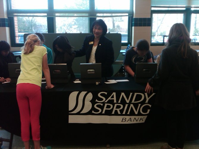 Nga Le, Sandy Spring Bank branch manager, Merrifield Office, assists students making banking deposits at Fairhill Elementary School's in-school banking day.