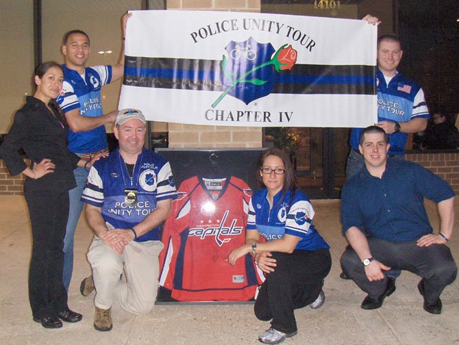 City of Fairfax police participated in a Police Unity Tour fundraiser on Tuesday, April 16, at Coyote Grille in Centreville. Raffled off was this Washington Capitals jersey. Holding banner (back row, from left) are City of Fairfax Police Officers Robert Mignon (K-9) and Jay Tolan (patrol). (Front row, from left) are Christine Castro, Coyote Grille; federal agent Kevin Whalen; U.S. Park Police Officer Lisa Marie Weisbaum; and Randall Henderson, Coyote Grille.