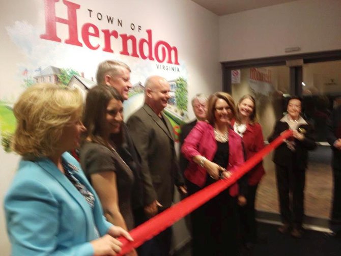 Mayor Lisa Merkel cuts the ribbon, formally accepting the mural, while CAH President Michael O’Reilly, artist Keith Naquin and members of the Herndon Town Council look on.
