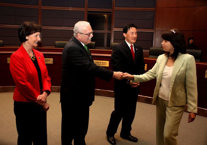 Bulova, Connolly and Keam congratulate one of the 100 new U.S. citizens who were sworn in Friday at a ceremony at the Fairfax County Government Center.