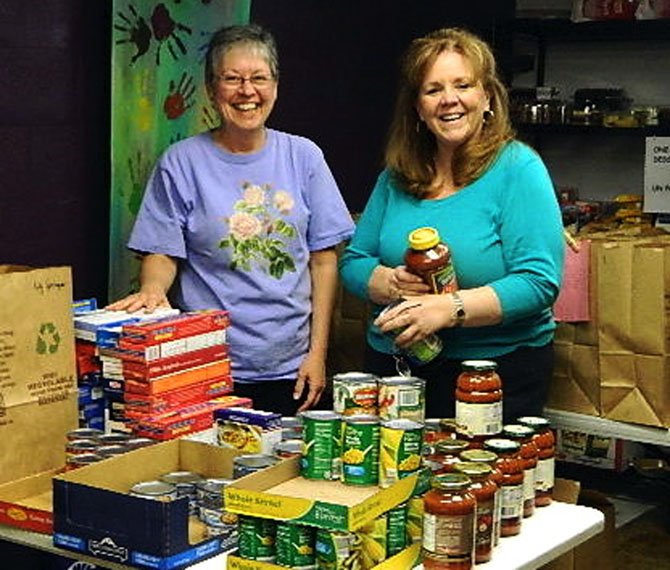 Debra Bessert and Lorraine Grant load the Homebound grocery bags in Rising Hope’s food pantry. 