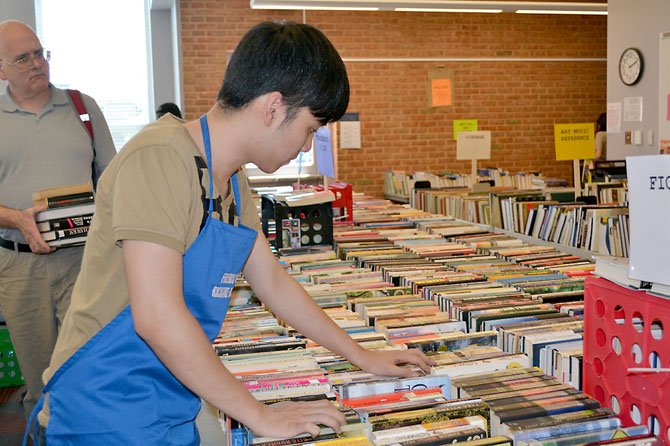 Friends volunteer Bao Nguyen, a college student, makes sure the books are in order for prospective buyers.