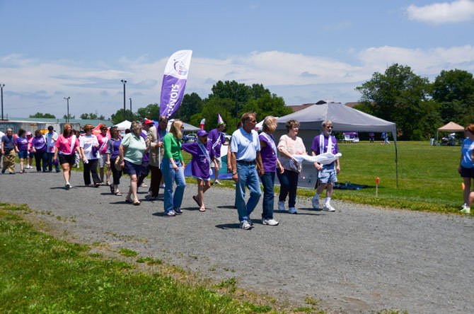 Teams of cancer survivors and their friends walk a lap around the Herndon Middle School track.