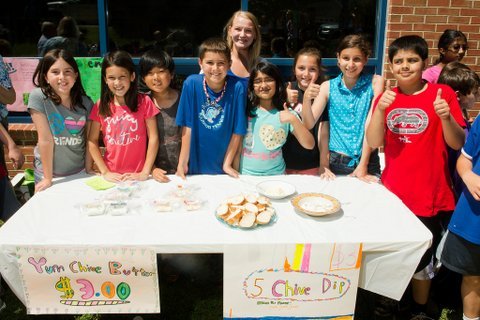 Churchill Road fourth graders Emily Mortman, Arielle Moore, Alewx Zaccardelli, Kevin Kaldes, (fourth grade teacher) Aubrey Beiswenger, Areej Khatri, Jenna Ashtar, Zoe Hendriks and Mazin Khan provide free samples of the chive butter and dip they made from homegrown chive plants at their farmer’s market June 4th.