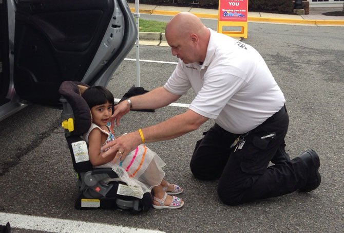 Sheriff Tim Gerard of the Arlington Sheriff's Department checks the fit of a car seat for 3-year-old Aman Rahman, who attends the Center for Alexandria's Children's playgroup. 