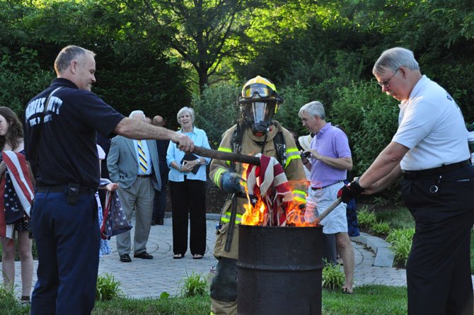 From left, Capt. Michael Allen, firefighter Liezel D’souza and Great Falls Volunteer Fire Chief Frank Smith assist the Children of the American Revolution in their annual Flag Day ceremony, properly disposing of damaged and worn American flags. 