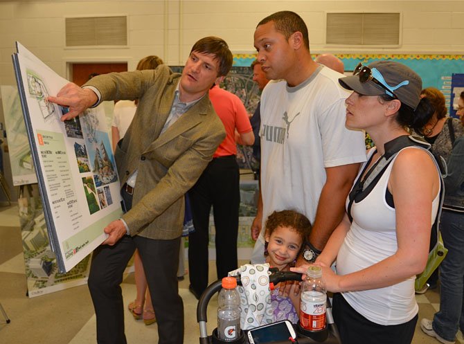 Jay W. Klug, principal with Tysons West developer JBG Rosenfeld, points out the highlights of the mixed-use project to Vienna residents Aaron and Jackie Hughes. Daughter Giuliann wasn’t quite as interested as her parents in a new urban-style Walmart currently included in the plans.