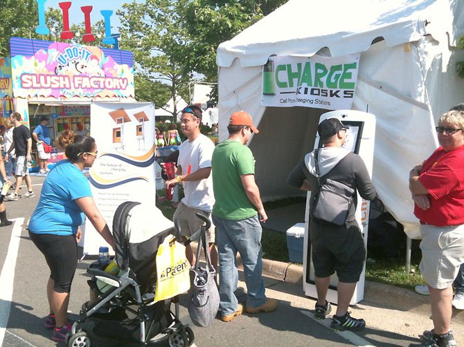 Celebrate Fairfax festival-goers with near-dead, powering off phones experience sweet relief upon finding a plug-in station at the iCharge Kiosks booth, which charged 300 dying phones over the festival, June 7-9.
