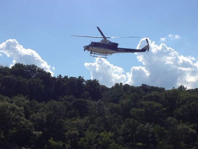 A helicopter flies low through Potomac River gorge searching for a swimmer who didn't make it back to shore.