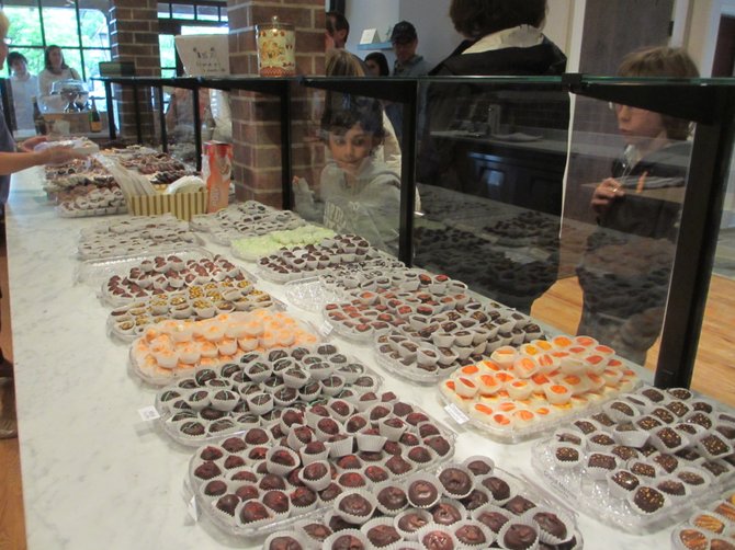 A child peers behind a glass barrier at the counters laden with chocolates at Cocoa Vienna.
