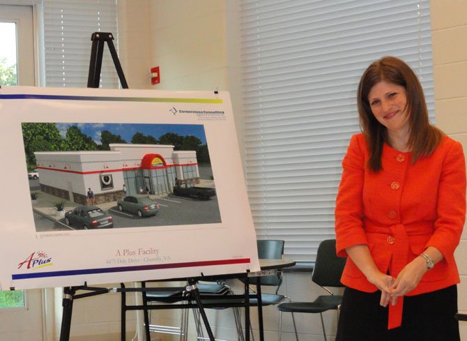 Sara Mariska stands next to an artist’s rendition of the new convenience store.