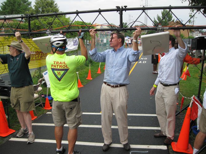 Sen. Mark Warner, a regular cyclist and W&OD trail-user, helps hoist up the timing bridge before the race begins.
