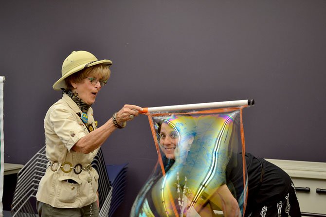 Safari Bingo creates a gigantic bubble around the head of a librarian at a children’s event at Burke Centre Library in June 2013. The library was scheduled to be one of two libraries tested with a reorganization plan on Sept. 1. That plan has been put on hold after criticism from library volunteers, staff and patrons.