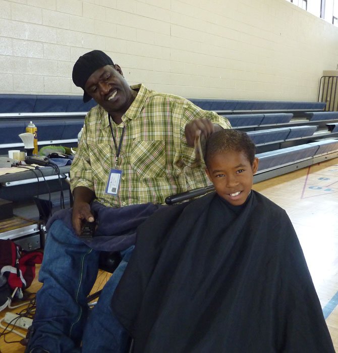 Del Ray barber Gary Bailey gives Tim Wiggins a haircut during the first Cuts for Kids Day. This year's back-to-school event will take place Aug. 26-28 at area recreation centers.