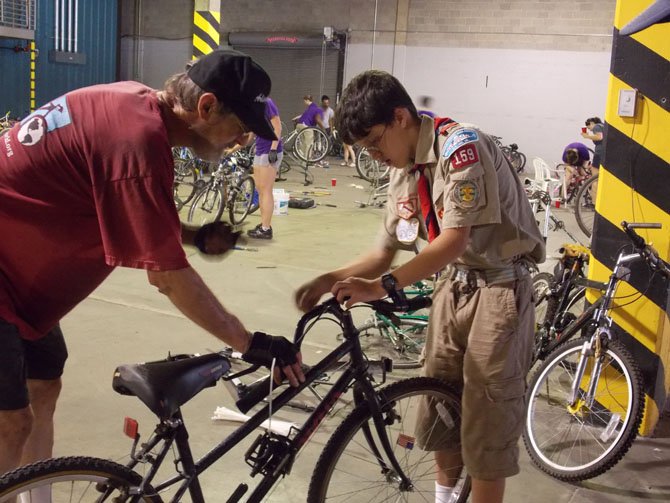 Keith Oberg, head of Bikes for the World, teaches Life Scout Conor Mears how to prepare the donated bikes for shipping.
