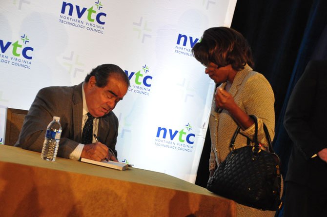 Associate Justice of the Supreme Court Antonin Scalia signs a copy of his book, “Making Your Case” for Karen Smaw Wednesday, Sept. 25 after addressing the Northern Virginia Technology Council.