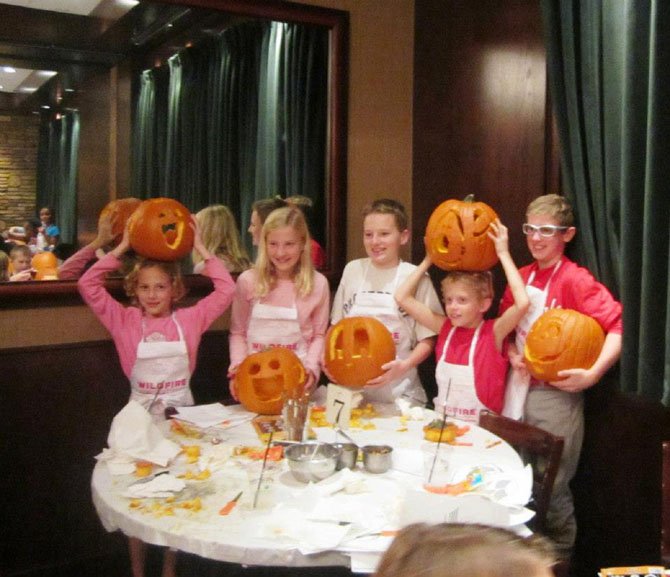 Local children show off their masterpieces after a pumpkin carving class at Wildfire Tysons Galleria. Proceeds from the class go to Food for Others, a Northern Virginia food bank.
