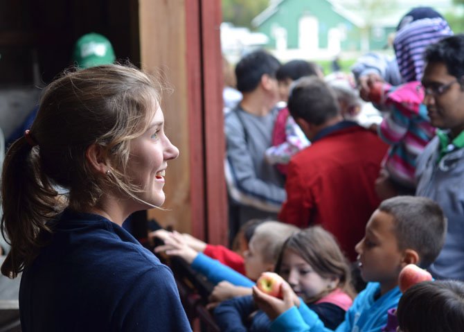 Frying Pan Park employee Kelsey Richard answers questions while visitors watch cider being made.

