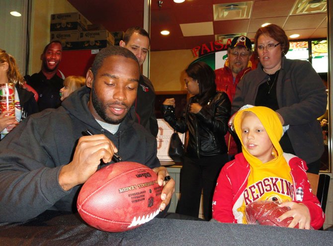 Tara Sankner watches Pierre Garçon autograph a fan’s football; in the background are Fouad Qreitem and Craig and Tammy Sankner.
