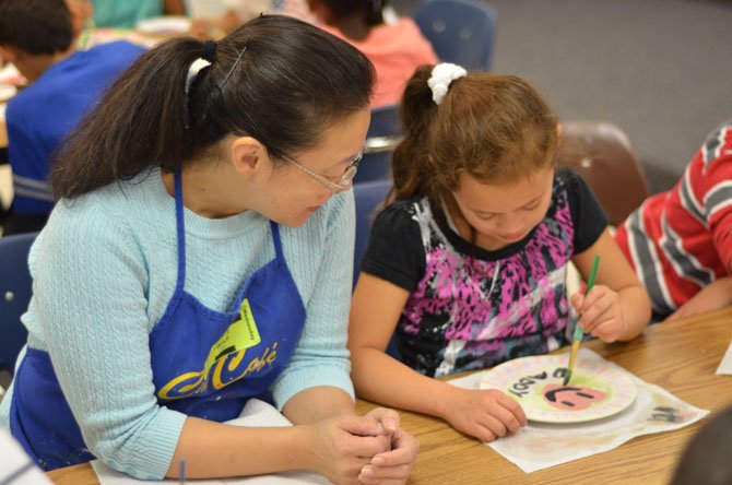 Grace H. Wolf chats with a 3rd grade student in Jean Peretzman's class. The Council for the Arts of Herndon (CAH) funds Wolf's art outreach program. 