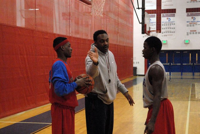 T.C. Williams head boys’ basketball coach Julian King talks to Warren Smith, left, and Darius Holland during practice on Monday.