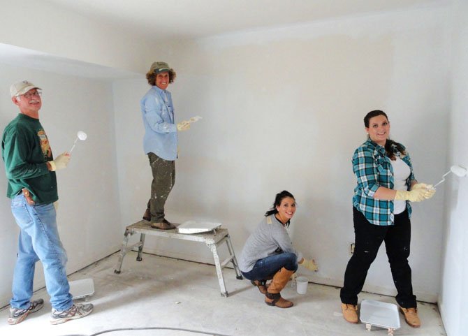 Painting the living room are (from left) sandlot volunteers Craig Taylor and Laurie Corkey and FM Global’s Mercedes Powers and Dallas Gage.