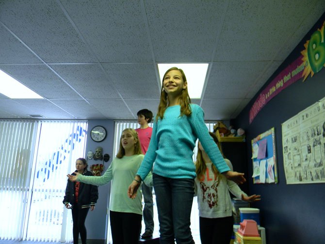 Margarita Gamarnik, playing Millie, stands on a set box rehearsing the performance with fellow cast members.