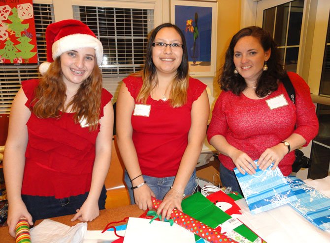 Wrapping children’s gifts at the family shelter are (from left) Lake Braddock sophomore Liz Barr and Robinson sophomore Carolina Gonzalez, both of Girl Scout Troop 870 of Burke, plus Liz’s mom, Evangeline Barr.