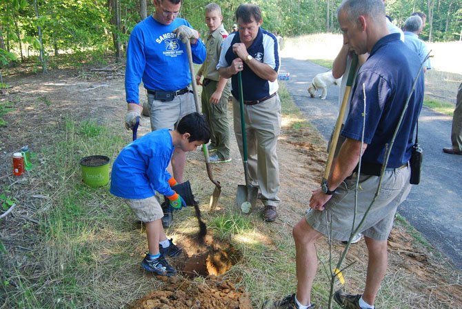 Virginia Delegate Dave Albo, Springfield Supervisor Pat Herrity and a representative from the Fairfax County Parks Authority help a volunteer from Boy Scouts from Troop 1140 at Burke Lake Park. The "1,000 Trees in 1,000 Days" program, launched by the 95 Express Lanes project private partners Transurban and Fluor in 2012, aims to restore greenery to areas that lost trees during construction of the express lanes.