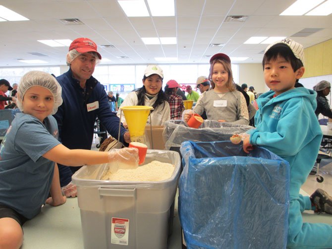 Blake Snider, 9, Harvey Snider, Lily Qin, Lauren Snider, and Lang Xiong, work together to fill a meals package that feeds four.