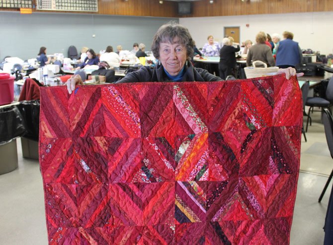 Fairfax Station resident Joan McGowan presents her quilt for the Wounded Warriors project at a Springfield Quilters’ Unlimited workshop. McGowan has held membership in Springfield Quilters’ Unlimited longer than any other member in the group. 
