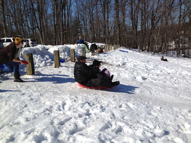 Families spend the snow day on Friday afternoon sledding on the hill beside the Children’s House Montessori School on Wiehle Avenue in Reston.