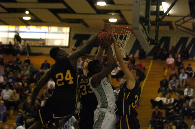 Three Lake Braddock defenders swarm South Lakes guard Brandon Kamga during the 6A North region semifinals on Feb. 28.